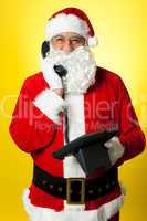Smiling aged Santa attending phone call