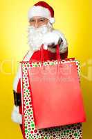 Cheerful Santa holding vibrant colored shopping bags