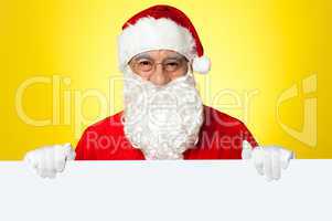 Male Santa standing behind big blank banner ad board