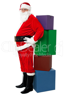 Santa leaning over colorful pile of Xmas presents