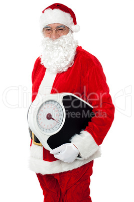 Aged male Santa holding weighing scale