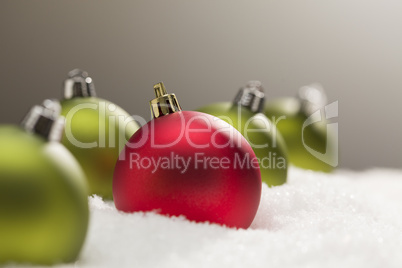 Red and Green Christmas Ornaments on Snow Over Grey