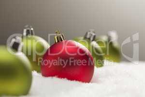 Red and Green Christmas Ornaments on Snow Over Grey