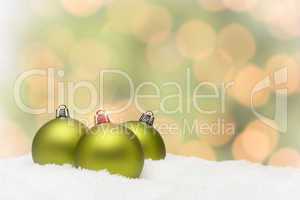 Green Christmas Ornaments on Snow Over an Abstract Background