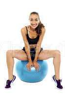 Beautiful smiling fit lady relaxing on big swiss ball