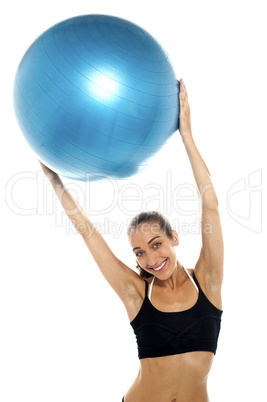 woman holding big blue pilates ball above her head