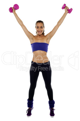 Strong woman lifting the dumbbells high in the air