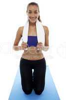 Woman in gym wear kneeling on blue mat