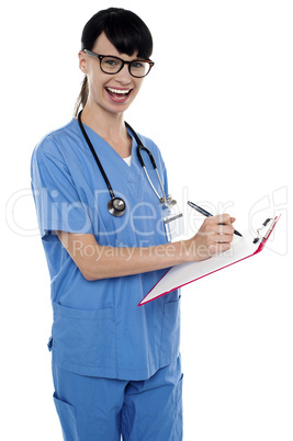 Medical nurse jotting down notes on writing pad