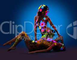 Nude women with glow uv body art and flowers