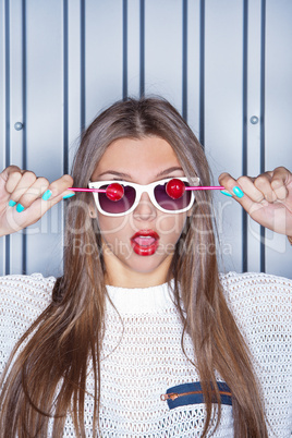 a beautiful young girl with two red lollipops near the wall