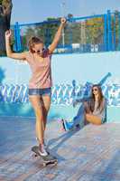 two beautiful young girls wearing sunglasses in an empty pool