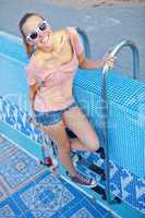 a beautiful young girl with a skateboard on the pool ladder