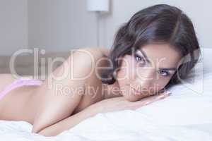 Beautiful young brunette woman lying on bed
