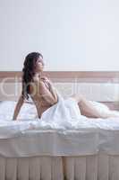 Beautiful brunette woman in towel on bed