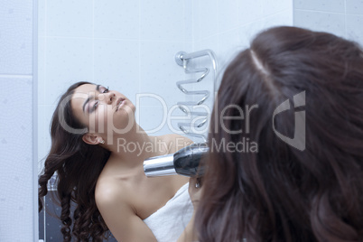 Brunette woman with hairdryer in bathroom