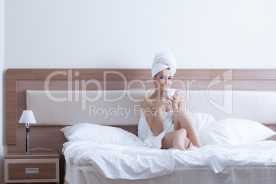 Young woman drinking coffee in bedroom