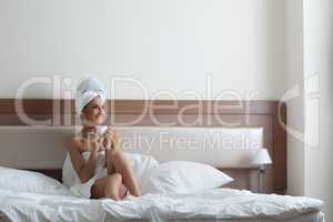 Happy young woman drinking coffee in bedroom