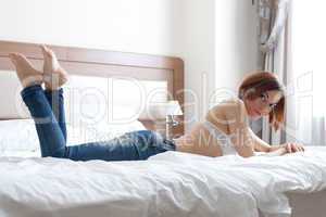 Pretty woman in jeans and white bra on big bed