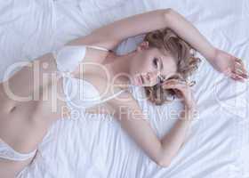 pretty woman posing in bed wear white lingerie