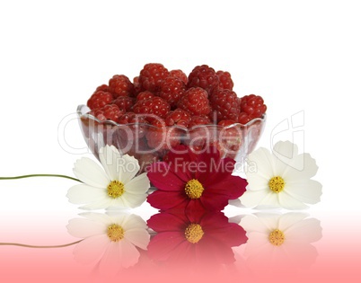 Berry raspberries in a glass vase on a table with flower