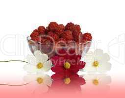 Berry raspberries in a glass vase on a table with flower