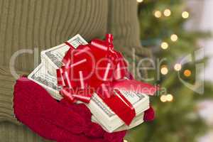 Woman Wearing Mittens Holding Stacks of Money with Red Ribbon