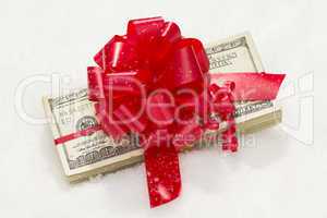 Stack of Hundred Dollar Bills with Red Ribbon on Snow