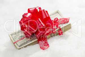 Stack of Hundred Dollar Bills with Red Ribbon on Snow