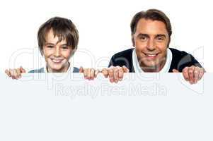 Father and son posing behind big blank banner ad