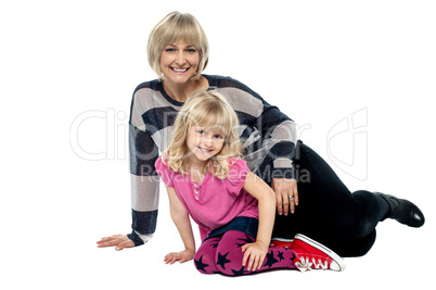 Cheerful mum and daughter sitting on studio floor