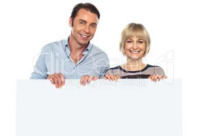 Lovely couple standing behind blank billboard