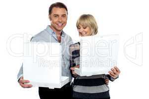 Middle aged couple holding white pizza boxes