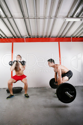 Group of two people exercising using barbells in gym and kettleb
