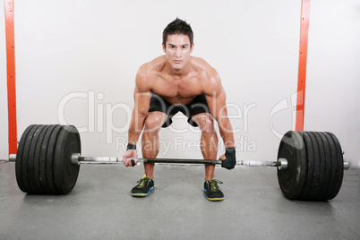 Young and muscular guy holding a barbell.  Crossfit dead lift ex