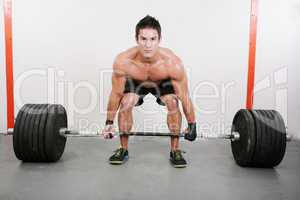 Young and muscular guy holding a barbell.  Crossfit dead lift ex