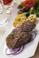 Steak mit Kartoffelhälften und Salat