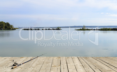 Fishing rod lying on a wooden platform at the river