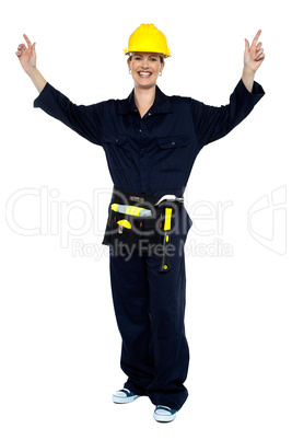 Smiling lady worker in jumpsuit raising her hands