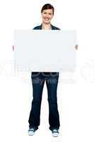 Fashionable trendy woman holding blank ad board