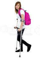 Teenager student holding crutches and walking