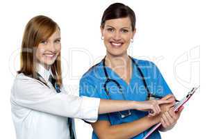 Attractive girl pointing at the doctors case sheet