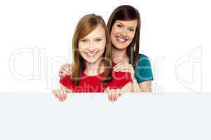 Girl holding ad board with her mother behind her