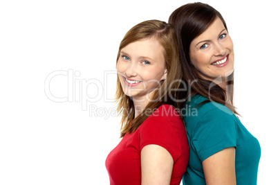 Joyous trendy mom and daughter standing back to back