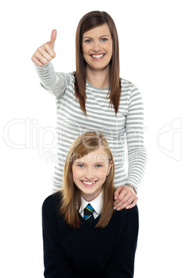 Cute schoolgirl with her mom. Mother gesturing thumbs up