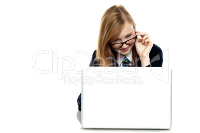 Girl adjusting her spectacles while working on laptop