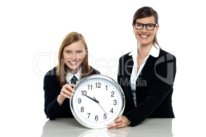 Pretty student holding clock with her teacher