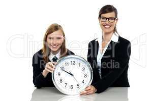Pretty student holding clock with her teacher