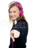 Pretty musical girl enjoying music and pointing at you