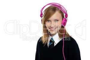 Cute teenager listening to music through headphones